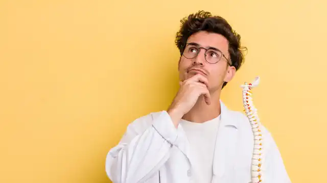 Man pondering which massage is best for back pain holding a model of a spinal column